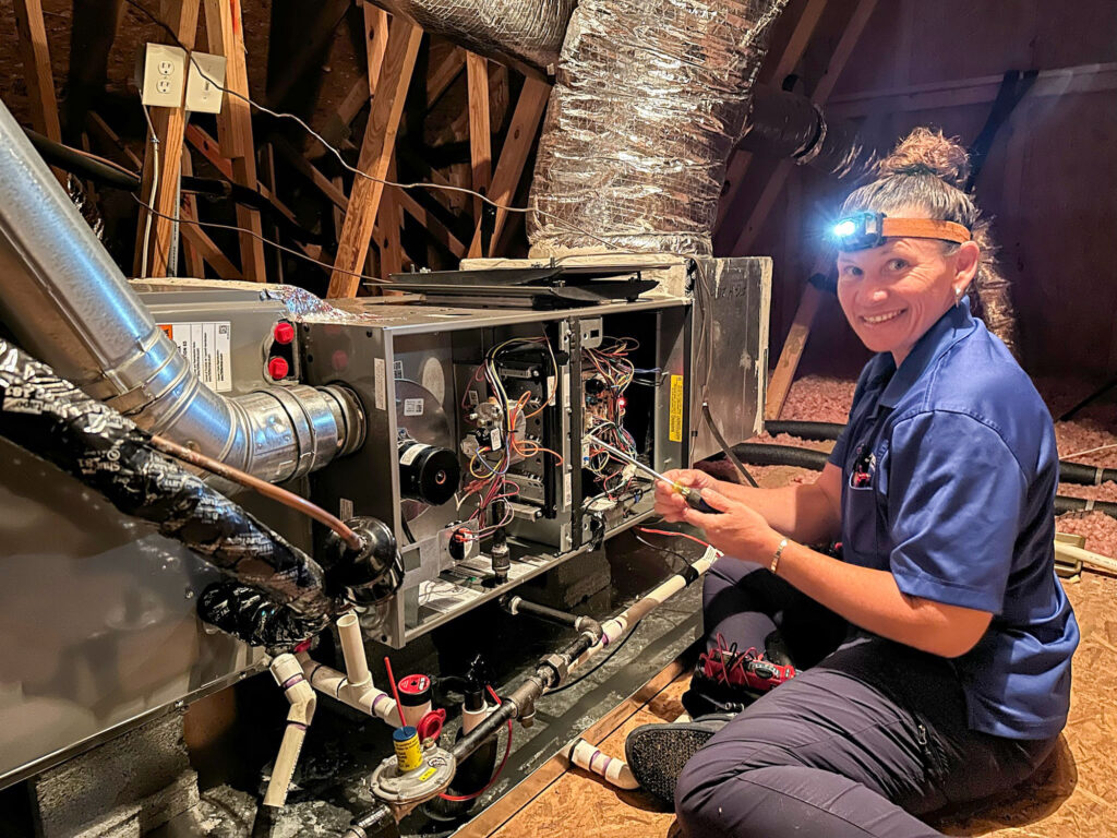 Andersen technician troubleshooting a gas furnace in a Charlotte attic
